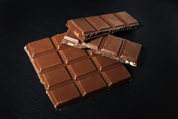 chocolate bar on black background. milk chocolate on black stone