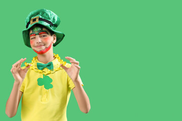 Funny boy with face painting, golden chain and leprechaun's hat on green background. St. Patrick's...