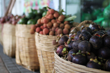 Baskets of fresh tropical fruits including lychee, mangosteen, and citrus fruits displayed at a vibrant Vietnamese market in wicker baskets