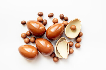 Broken and whole chocolate egg on white background, top view. Chocolate background