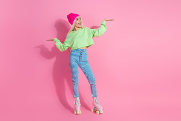 Young Fashionable Woman in Trendy Sportswear with Roller Skates Standing on Pink Background in Playful Pose Showcasing Fun Lifestyle