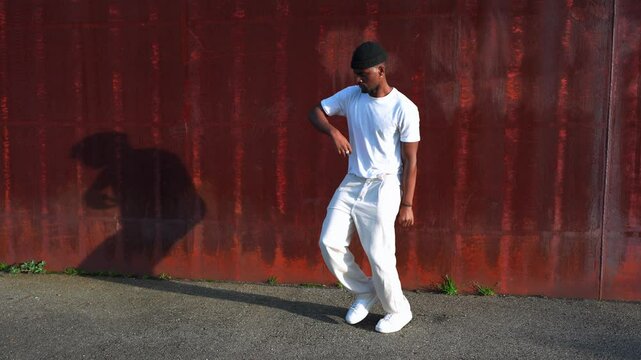 Young african american male dancer performing dynamic hip hop choreography in urban industrial setting, expressing artistic movement with passion and rhythm