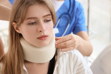 Injured young woman after accident with cervical collar visiting doctor in clinic, closeup