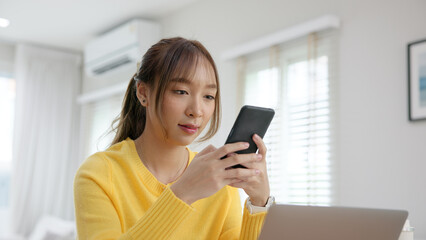 Naklejka premium Young woman AI talent workforce help ask job career plan. Adult female asia people happy smile sit digital nomad work at home typing asking ChatGPT chat bot mobile phone buy paying online chatbot app.
