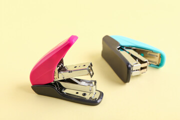 Different modern staplers on yellow background