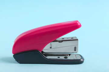 Pink stapler on blue background