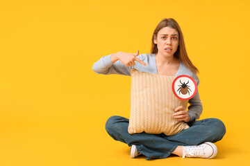 Young woman with pillow and mite sign suffering from allergy on yellow background