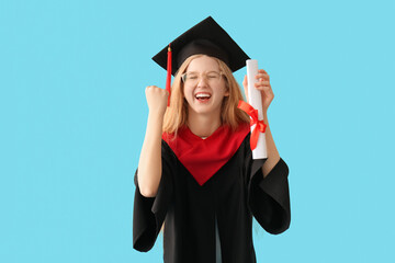 Happy female graduating student in mortar board with diploma on blue background