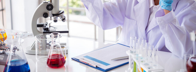 Banner Scientist woman holding chemical test yellow glass tube testing science laboratory. Lab technician holding gold fluid dropper glass tube Urine sample. Asian woman scientist with copy space