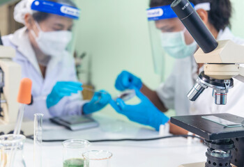 Scientist man woman working together team partner look into Microscope research in science laboratory. Two Asian scientist use microbiology microscope chemistry lab equipment. Biochemistry researcher