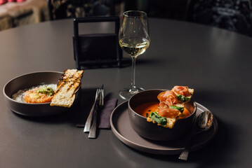 Salmorejo soup - Spanish tomato puree soup with a rich flavor of roasted vegetables such as bell pepper and shallots, enriched with cream and butter. Garnished with prosciutto and pesto sauce.