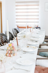 Fresh macarons in a three-tiered tray on a long table.