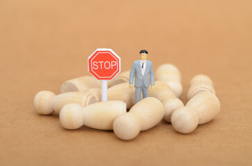 Human Trafficking Concept: Lone Figure Controlling Faceless Wooden Figures with STOP Sign