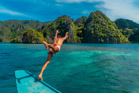 Tourist diving from a bangka boat in the turquoise water of coron island, philippines