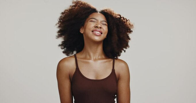 Hair, shake and beauty with face of woman in studio for shampoo, volume and self care. Curly hairstyle, natural texture and growth cosmetics with African person on white background for salon glow