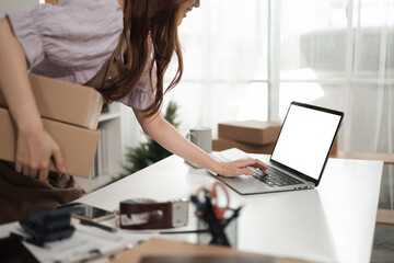 A Close-up of a small business owner multitasking, balancing package shipments while checking...