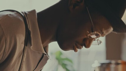 Inspired Black pianist in hat and glasses playing the piano during live jazz performance or rehearsal. Close-up, tilt up shot