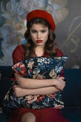 Vintage portrait of a disgruntled girl in a red beret with a pillow