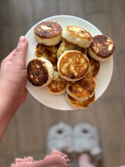 A woman's hands are holding a plate of cheesecakes.