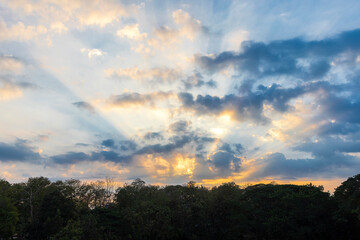 Golden sunlight pierces through scattered clouds, casting a warm glow over the horizon. A breathtaking sunrise paints the sky in hues of orange and blue, blending nature's beauty in perfect harmony.