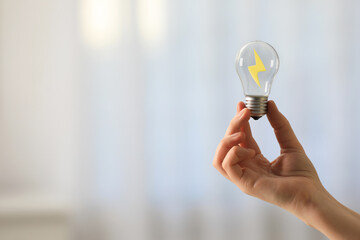 Woman holding light bulb with lightning inside on blurred background, closeup. Concepts of idea, startup, innovation, creativity and energy efficiency