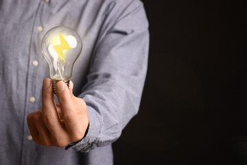 Man holding light bulb with lightning inside on black background, closeup. Concepts of idea,...