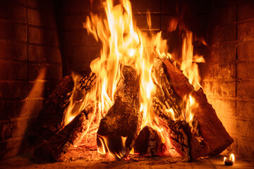 Obraz premium Fire burning in a fireplace, wood logs, flames. Warm home, heat. Christmas holiday.