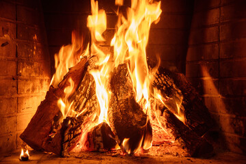 Fire burning in a fireplace, wood logs, flames. Warm home, heat. Christmas holiday.