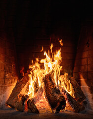 Fire burning in a fireplace, wood logs, flames. Warm home, heat. Christmas holiday.