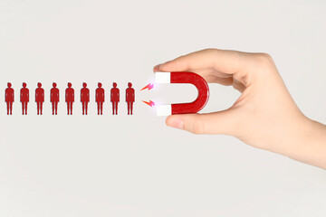 Woman attracting red human figures with magnet on white background, closeup. Recruitment or...