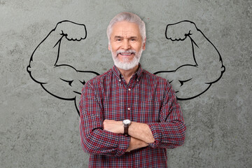 Happy man with drawing of strong arms behind him on grey background