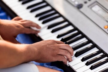 Obraz premium Close-up of male playing electronic keyboard with skilled hands outdoors