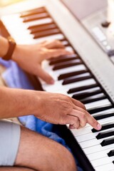 Obraz premium Male adult playing electronic keyboard indoors with focus on hands and musical notes