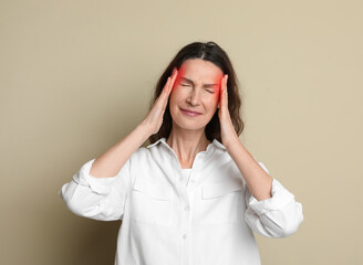 Woman suffering from headache on beige background