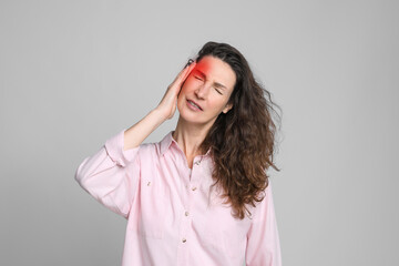 Woman suffering from headache on grey background
