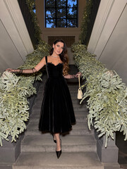 beautiful woman with dark hair in luxurious evening dress with accessories posing on the stairs...