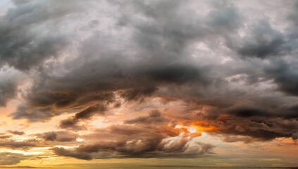 Obraz premium Bright sunset with setting sun behind vivid orange and yellow clouds