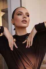 beautiful woman with dark hair in elegant burgundy dress and accessories posing in elegant interior