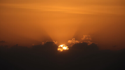 Naklejka premium Serene sunset with clouds partially obscuring the golden sun
