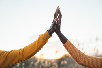 Two people giving high five outdoors at sunset celebrating success