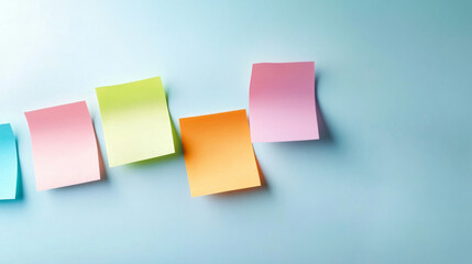 Fototapeta premium Five colorful sticky notes hanging on a pastel blue wall, creating a vibrant and minimalist composition with copy space