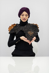 A stylish Muslim woman in a hijab presents her innovative handmade fashion accessory crafted from...