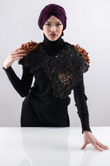A stylish Muslim woman in a hijab presents her innovative handmade fashion accessory crafted from...