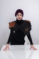 A stylish Muslim woman in a hijab presents her innovative handmade fashion accessory crafted from...