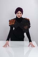 A stylish Muslim woman in a hijab presents her innovative handmade fashion accessory crafted from...