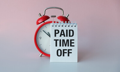 A red alarm clock with the words paid time off written on a white piece of paper