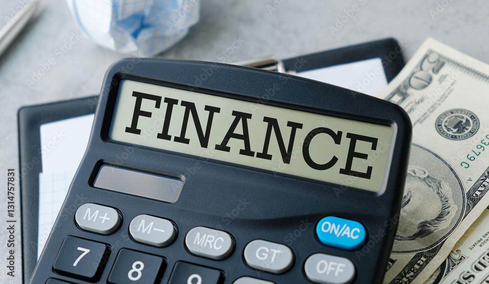Poster a calculator with the word finance on it. there is also a stack of money on top of it