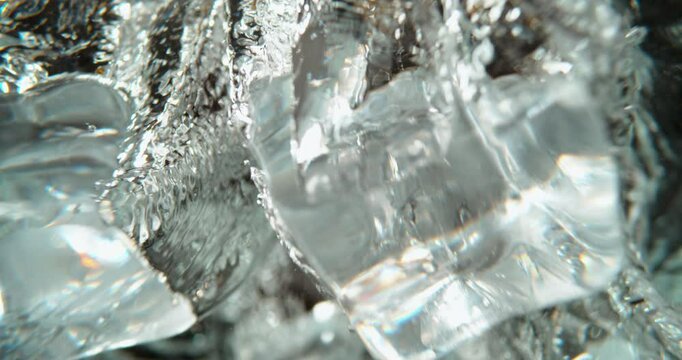 Pieces of ice cube falling into the water in slow-motion, Preparing beverage at the bar