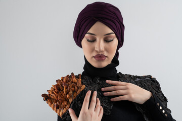 A stylish Muslim woman in a hijab presents her innovative handmade fashion accessory crafted from...