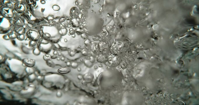 Macro close-up view of bubbles floating in a pot of boiling water, creating a mesmerizing texture. Concept of beverage